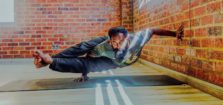 Man performing a yoga or acro-yoga pose horizontally against a brick wall